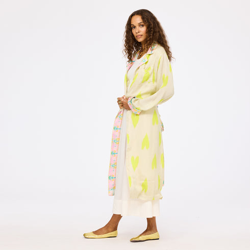 Kerri Rosenthal women's cream and neon lime green heart print maxi duster coat with pink floral contrast trim, layered over a white maxi skirt.