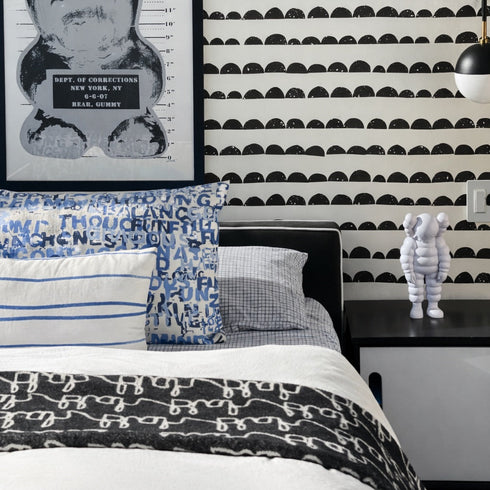 Bedroom with black and white patterned wallpaper, framed artwork, and decorative pillows.