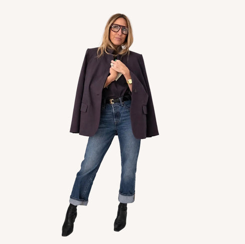 Woman wearing a coal blazer with cuffed jeans, black ankle boots, and glasses.