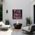 Kerri Rosenthal "Fireside + Kisses" pink word art painting displayed on outdoor patio wall above modern fire pit, black and pink typography canvas art styled with neutral outdoor furniture and potted plants