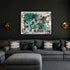 Black framed abstract painting by Kerri Rosenthal with teal, black and pink heart motifs displayed above gray sectional sofa in moody dark living room