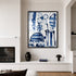 Black-framed blue and white abstract floral painting hanging above a built-in shelf with a dark ceramic vase and mushroom lamp, beside a fireplace in a minimalist living room.