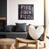 Kerri Rosenthal "Fireside + Kisses" painting in black frame displayed in boho-modern living room with woven chair, heart pillow, and live-edge wood