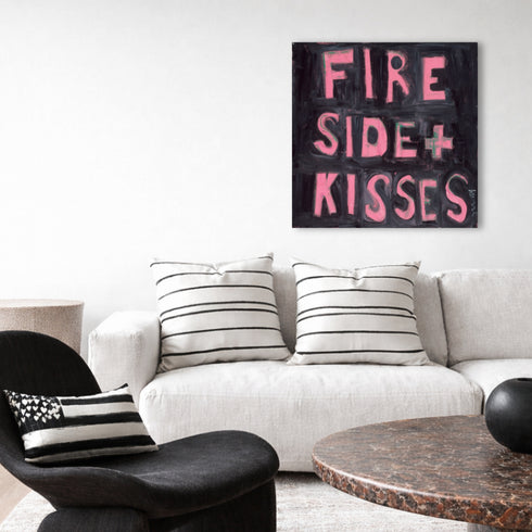 Kerri Rosenthal "Fireside + Kisses" original canvas art hung above white linen sofa with striped throw pillows, pink block letter painting in minimalist living room setting