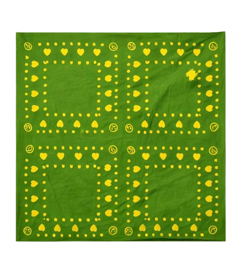 Close-up detail of green fabric with a yellow heart and dot border print and a smiley face icon by Kerri Rosenthal