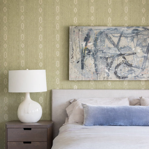 Bedroom with abstract painting on wall, lamp on nightstand, and bed with pillows.