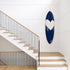Kerri Rosenthal navy heart surfboard displayed on a wall above a wooden staircase