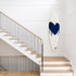 Kerri Rosenthal navy heart surfboard displayed on a wall above a wooden staircase