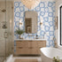 Modern bathroom with blue patterned wallpaper, wooden vanity, and white bathtub.