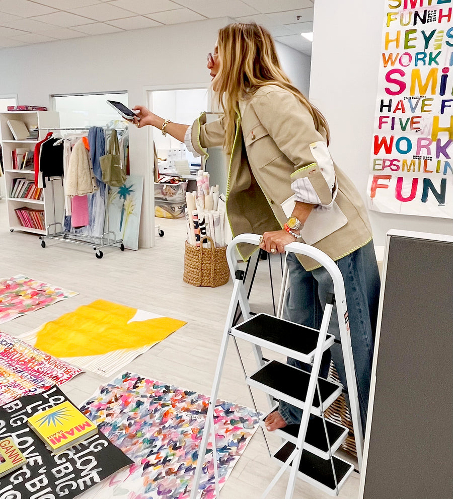 Kerri Rosenthal using a step ladder in a room with colorful decor and text on the wall.