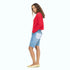 Woman wearing a red sweater and blue denim shorts on a white background