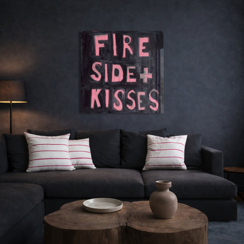 Kerri Rosenthal "Fireside + Kisses" pink and black word art painting above dark charcoal sofa with striped pillows, moody living room decor with wood coffee table
