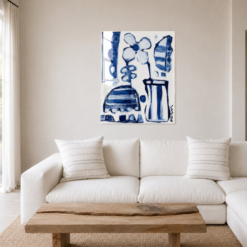 Plexi blue and white abstract floral canvas hanging above a white sectional sofa with Kerri Rosenthal Mr. Sharpie striped pillows, a live-edge wood coffee table, and sheer curtains in a bright living room. Artist Kerri Rosenthal