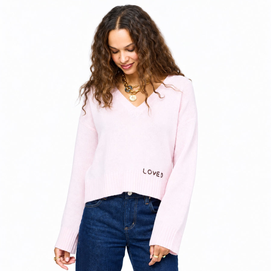 Model wearing Saturday V-Neck, an easy, relaxed-fit 100% cashmere sweater in hardly pink with hand-stitched "Loved" embroidery on hem.