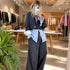 Mirror selfie of a woman wearing a blue striped art-print shirt layered under a navy blazer with matching wide-leg pants.