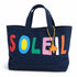 A navy blue canvas tote bag featuring the word 'SOLEIL' spelled out in colorful felt letters (red, blue, green, pink, white, orange) on the front, with a small orange felt sun hanging from a yellow string.