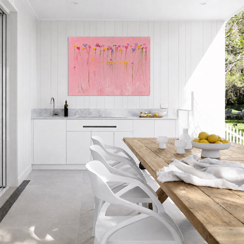 Kerri Rosenthal pink wildflower canvas art above white kitchen counter in coastal outdoor dining space