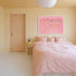 Kerri Rosenthal pink flower field painting in white frame above bed in pink and neutral bedroom