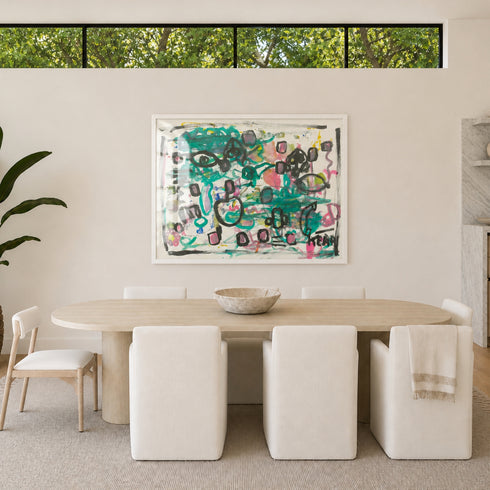 Framed abstract painting by Kerri Rosenthal with teal, black and pink heart and eye motifs displayed above dining table in modern neutral dining room