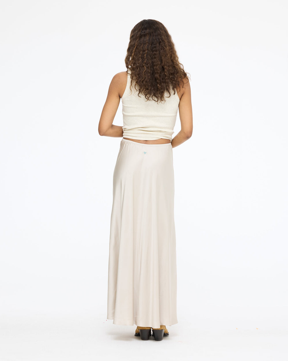 Model wearing the Ali Maxi Skirt in taupe with a white tank top, back view