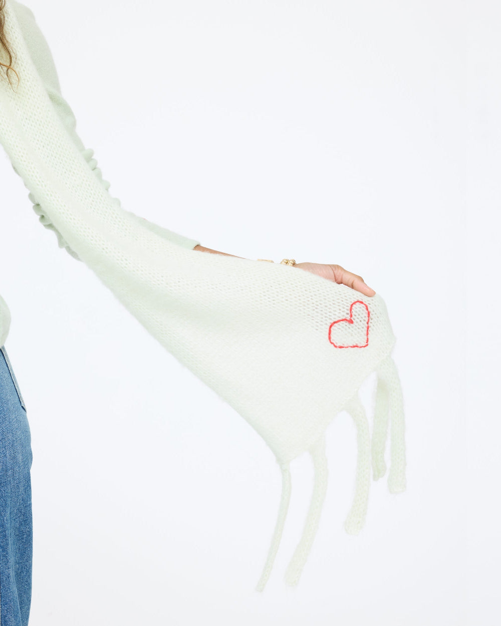 Close-up of the Cloud Hopping Scarf in pistachio showing the fringe and red heart, side view