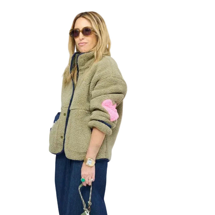 Side view of model wearing olive sherpa jacket with navy contrast trim, snap-button front, and heart-print lining peeking from sleeve.