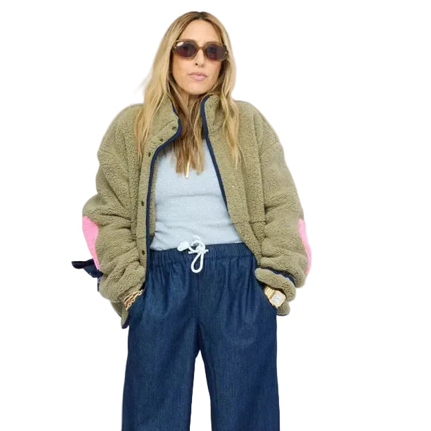 Model wearing olive sherpa jacket with navy contrast trim,  open snap-button front, and heart-print lining peeking from sleeve. Shop Kerri Rosenthal women's jackets.