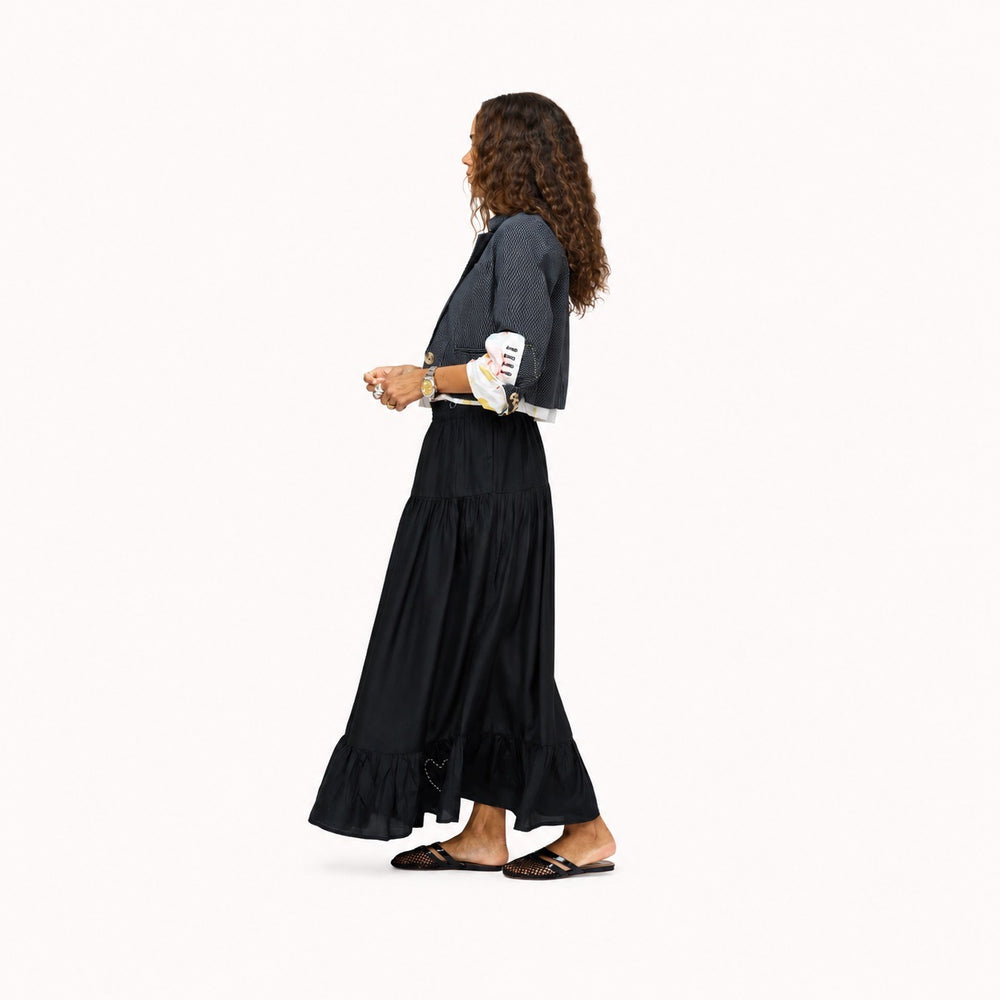Side view of model wearing a pale pink tank top  and a black tiered maxi skirt, paired with woven black flats. Women's clothing by Kerri Rosenthal