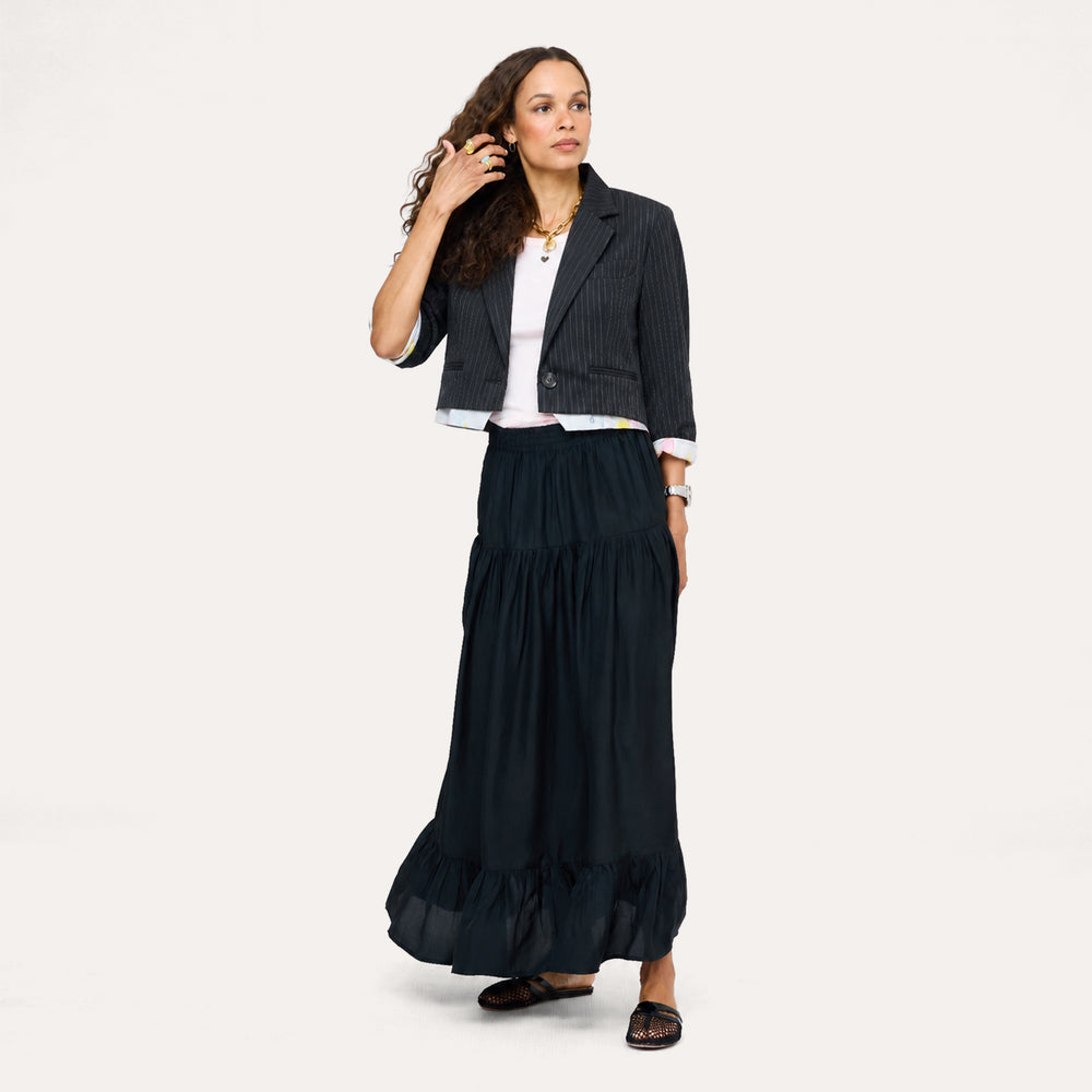 Model wearing a navy pinstriped cropped blazer over a white tee, styled with a black tiered maxi skirt and layered gold necklaces by Kerri Rosenthal