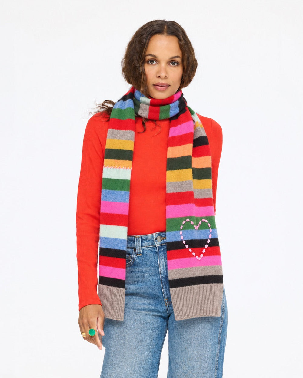 Model wearing the Fireside Scarf in multicolor stripe with a red mock neck top and jeans, front view