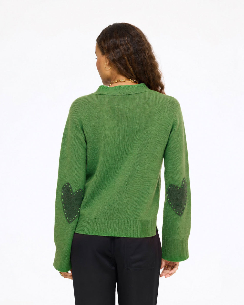 Model wearing the Frances Cardigan in evergreen with black pants, back view with heart elbow patches
