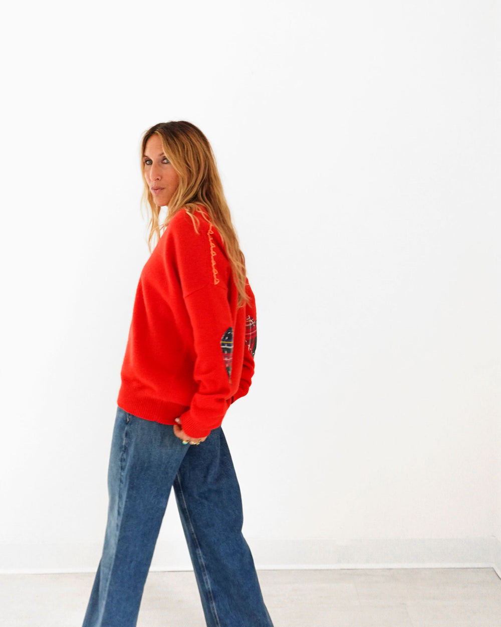 Kerri wearing the Frenchie Patchwork Sweater in red with jeans, side view
