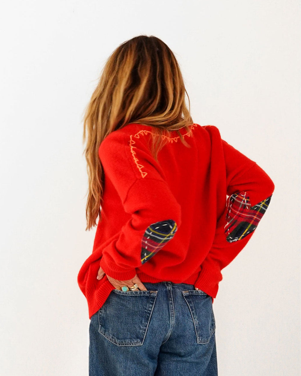 Kerri wearing the Frenchie Patchwork Sweater in red with jeans, hands on hips, back view