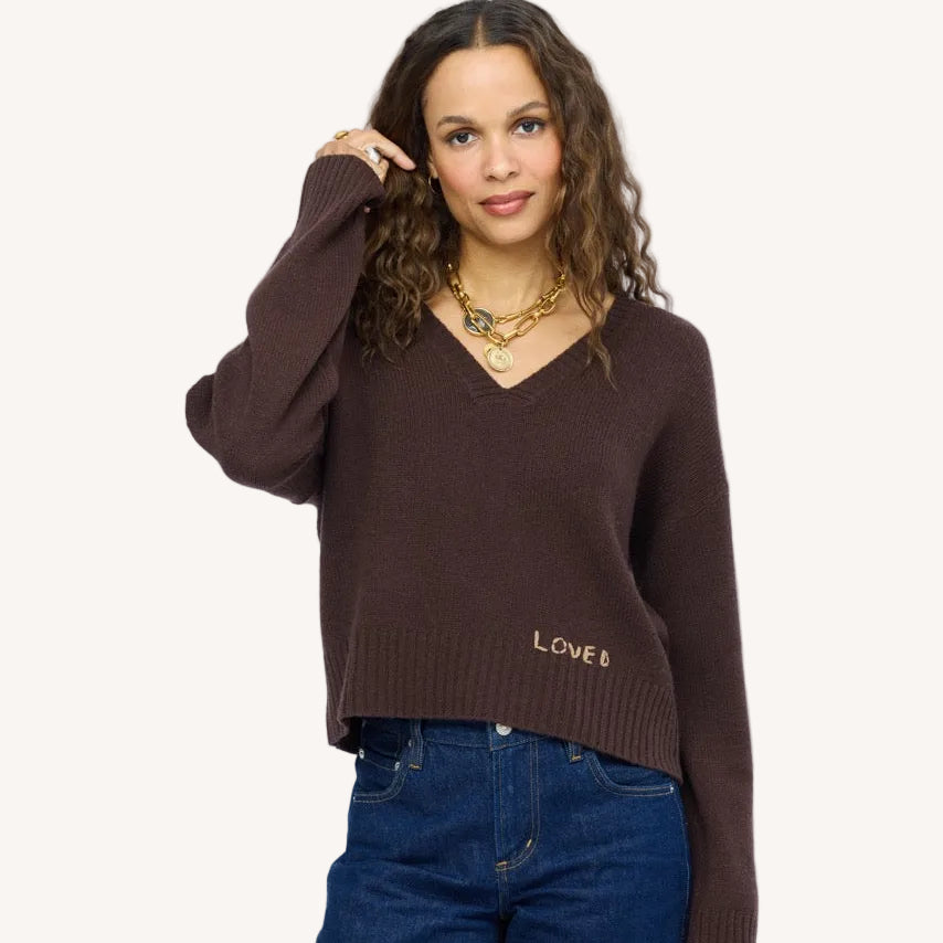 Model wearing Saturday Cashmere Sweater, made from 100% cashmere in Cocoa with a relaxed fit, a flattering V-neckline, and hand-stitched "Loved" embroidery.