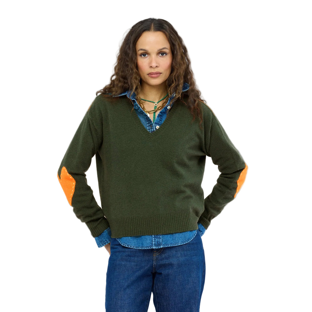 Front view of relaxed V-neck cashmere sweater in green with orange elbow patches, layered over a denim shirt. Shop Kerri Rosenthal sweaters.