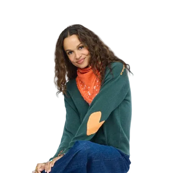 Kerri Rosenthal orange heart-print bandana worn as a headscarf, model seated in a teal cardigan