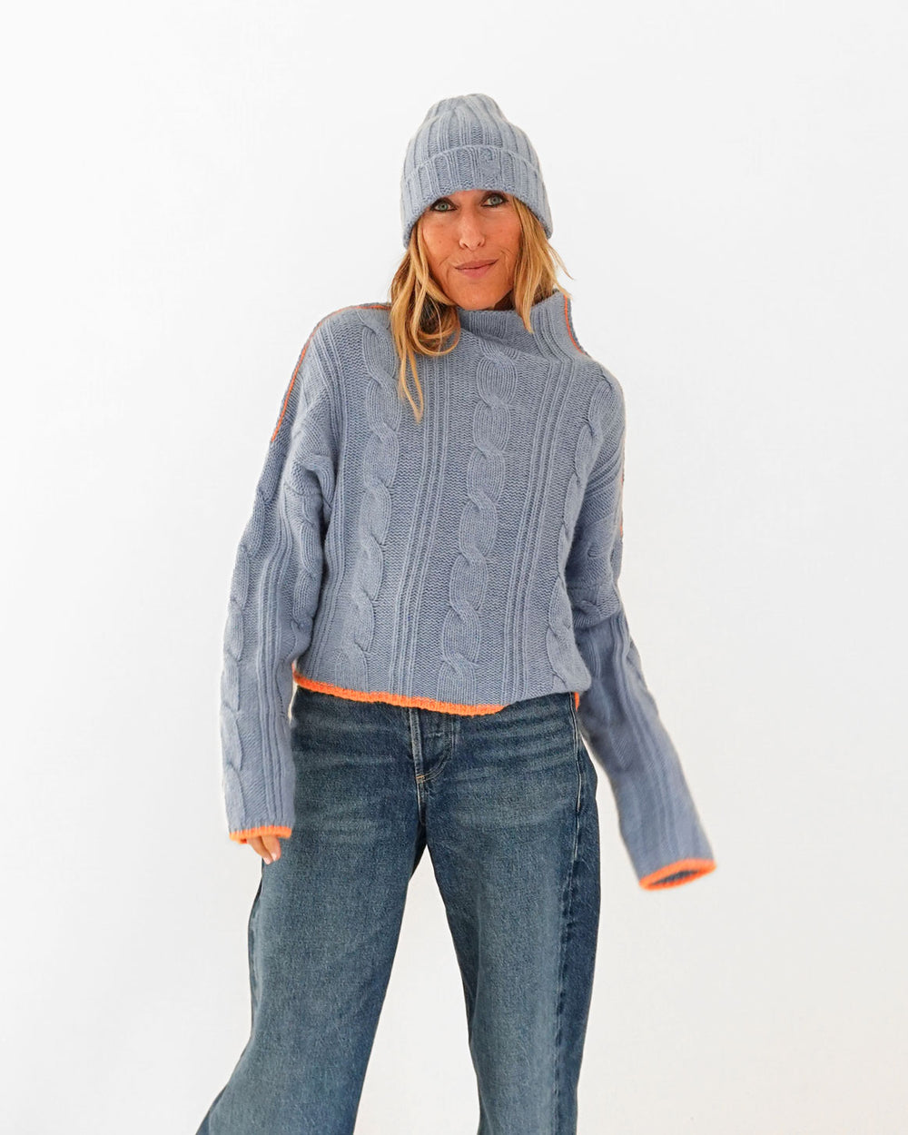 Kerri wearing the Winter Beanie in blue with the Hearth Sweater in blue and jeans, three-quarter front view