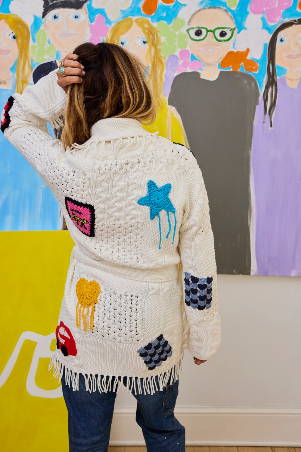 Back view of the Kerri Rosenthal Icon Sweater, showing the belted fringe waist tie and cable knit texture.
