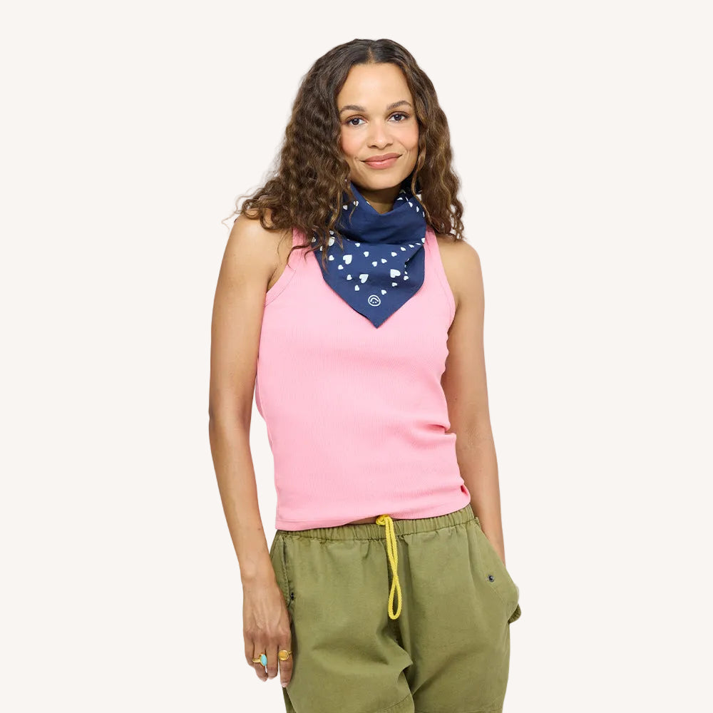 Woman wearing a pink tank top with a blue heart-print bandana scarf and army green drawstring pants.