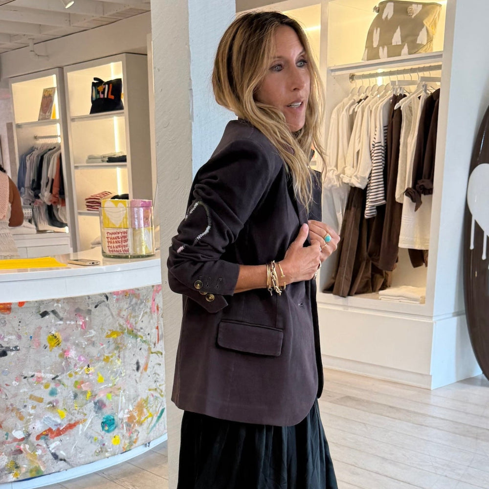 Kerri Rosenthal coal tailored blazer styled over black tiered maxi skirt, boutique lifestyle shot. Shop Kerri Rosenthal blazers