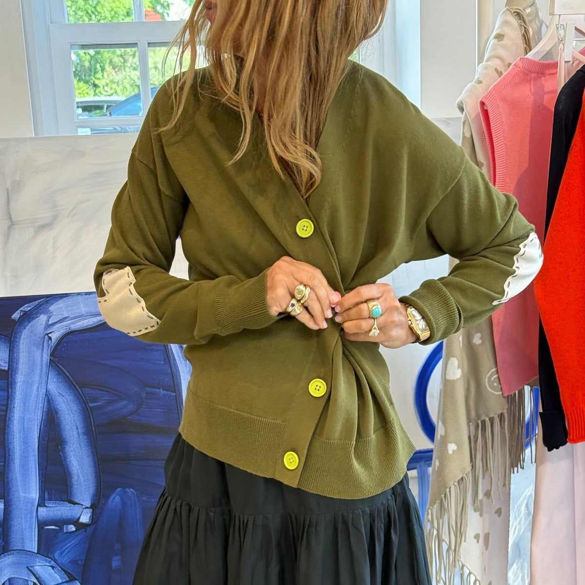 Olive green cardigan with yellow buttons, layered over red top and black maxi skirt