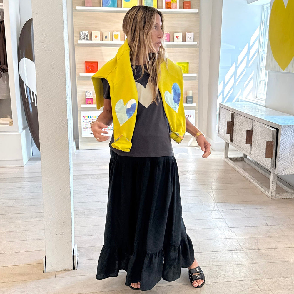Signature heart graphic tee with yellow sweatshirt layered over grey with black maxi skirt, everyday casual style