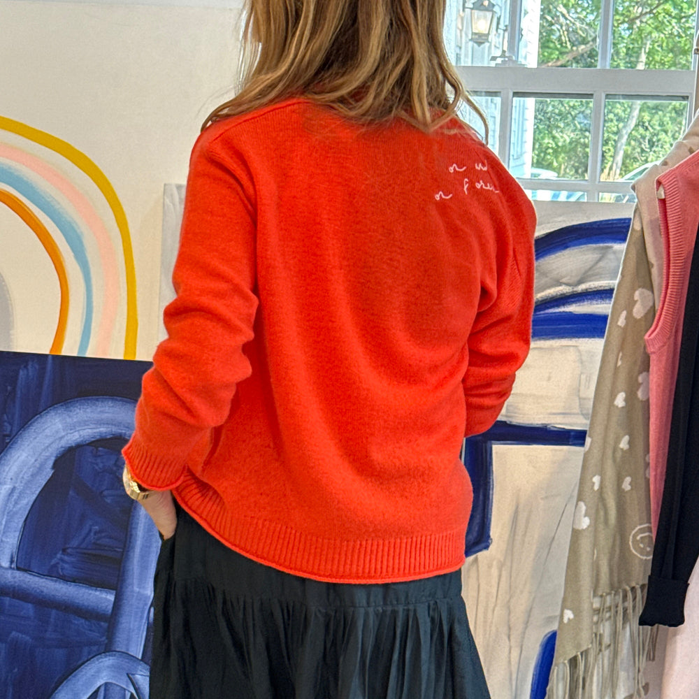 Back of woman wearing a tomato cardigan with and black maxi skirt.