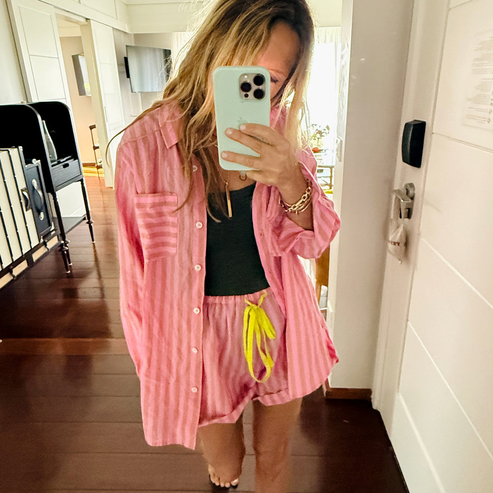 Women's pink and orange striped oversized button-down shirt and shorts set.

