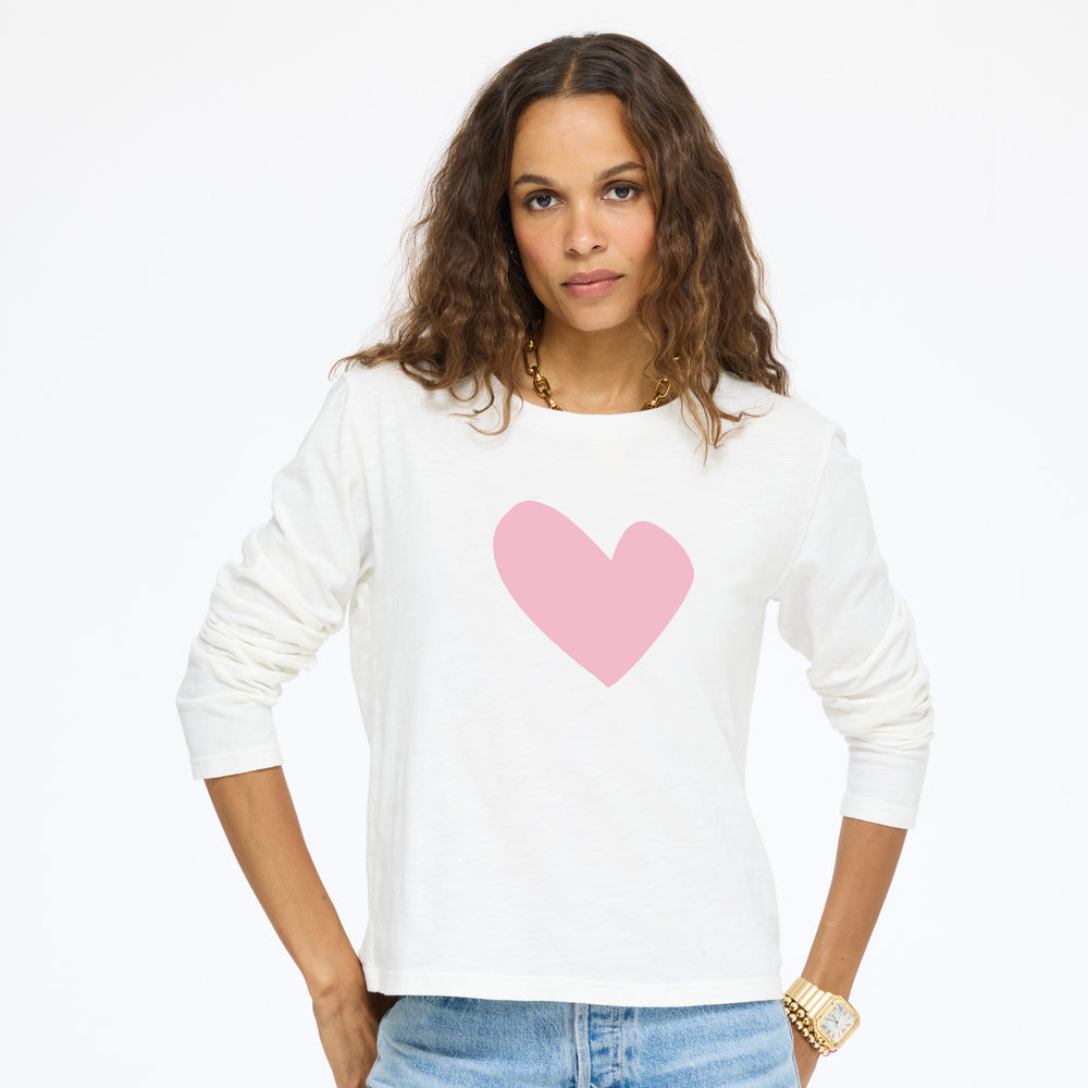 Model wearing the Long Sleeve Suke Imperfect Heart Tee in cream with a pink heart and jeans, front view