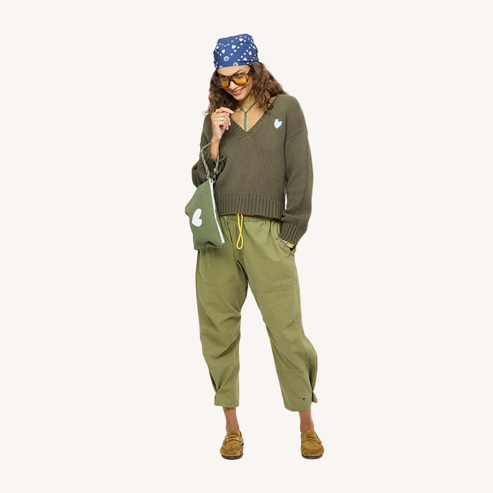 Woman wearing a blue heart-print bandana around head and army green v-neck sweater and matching pants.