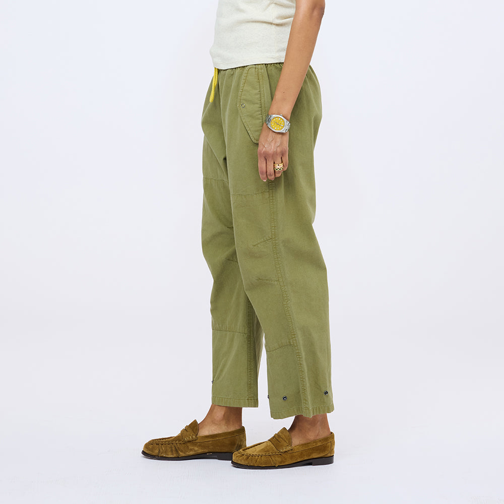 Side view of olive green drawstring pants with a cream top and tan suede loafers.