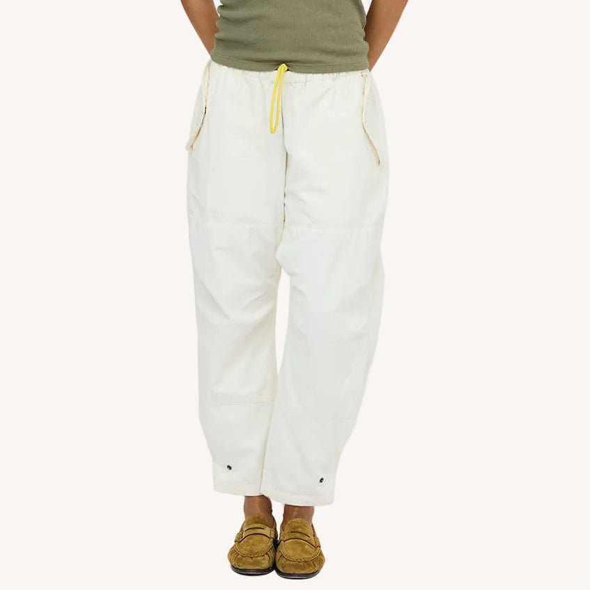 Close-up of natural white drawstring pants with an olive top and tan suede loafers. Shop women's pants at Kerri Rosenthal