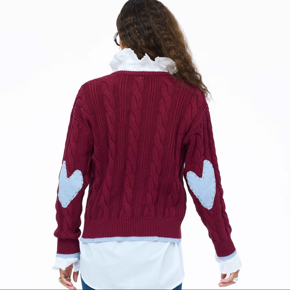 Kerri Rosenthal Maxwork Cable Pullover Sweater in Burgundy, back view showing cable knit texture and patchwork elbow detail, layered over a white shirt with jeans.
