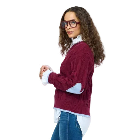 Kerri Rosenthal Maxwork Cable Pullover Sweater in Burgundy, woman standing in profile showing cable knit pattern and layered white shirt, styled with jeans and burgundy boots.